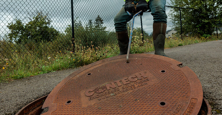 A close-up of a worker removing a stormwater system drain hole cover.